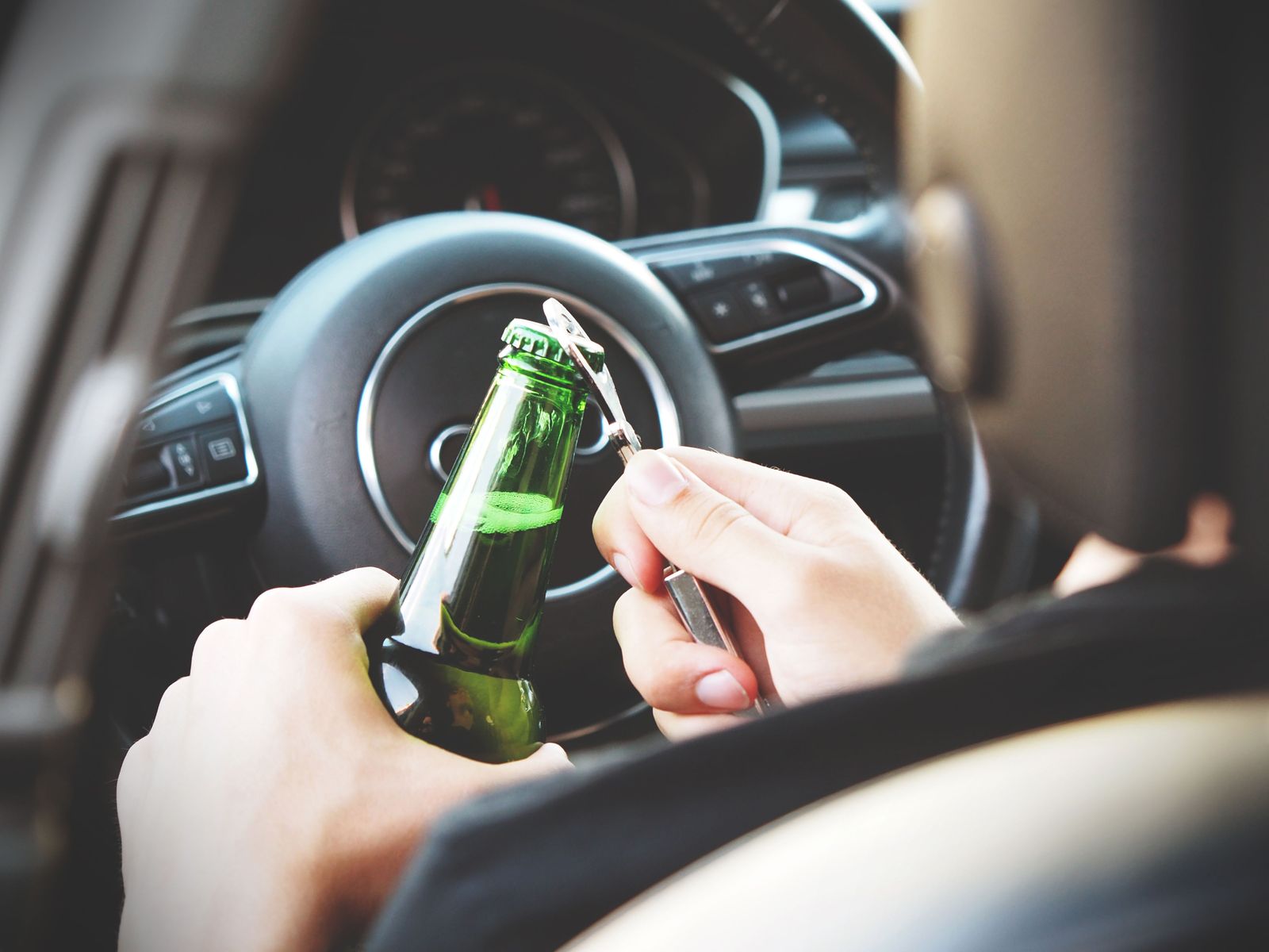 Driver holding a bottle behind the wheel